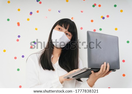 Beautiful asian thai long dark hair woman wearing white surgical mask using laptop isolate over white party background. Work from home concept. Business woman working with computer laptop.