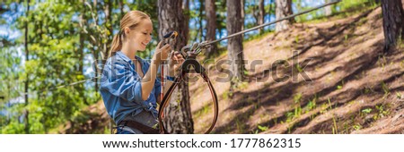 Young attractive woman in adventure rope park in safety equipment 