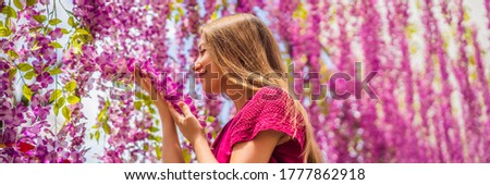 Beautiful young woman among pink flowers hanging down BANNER, LONG FORMAT
