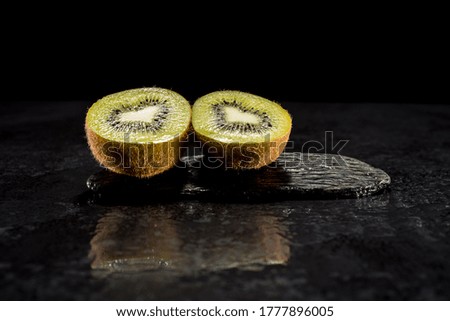 Creative pictures of fresh kiwis on slate and black background
