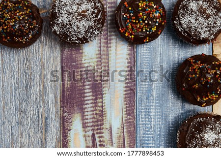 several chocolate cupcakes with decorations on the top and right side of the image on a background of coloured boards for a baby shower, photo taken from above, party concept, background, colours
