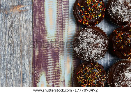 several chocolate cupcakes with decorations on the right side of the image on a background of coloured boards for a baby shower, photo taken from above, concept of party, background, colours, wood