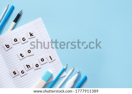 Text Back To School written by printed letters on white sheets of paper on notebook with blue school stationery on blue background with a copy space