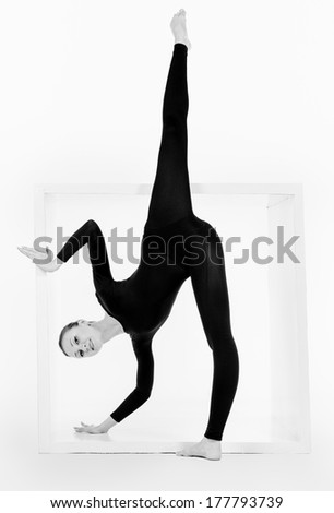 Modern ballet dancer posing with a cube at studio. Plastic body concept. Isolated over white.