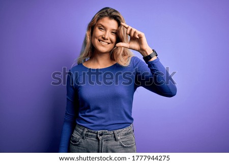 Young beautiful blonde woman wearing casual t-shirt over isolated purple background smiling and confident gesturing with hand doing small size sign with fingers looking and the camera. Measure concept
