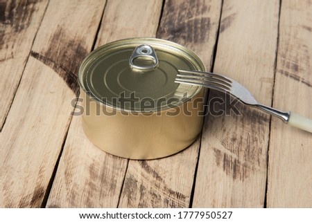 Food Can and Fork on a Wooden Table. Packaging, product. Storage of food for a long time.