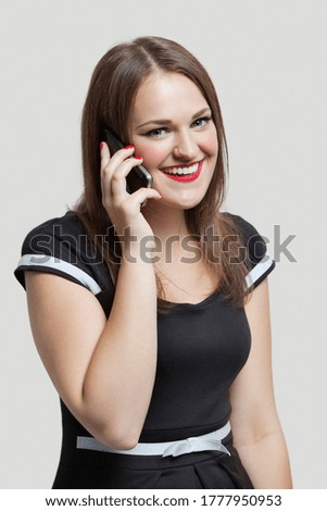 Portrait of young woman communicating on cell phone over gray background