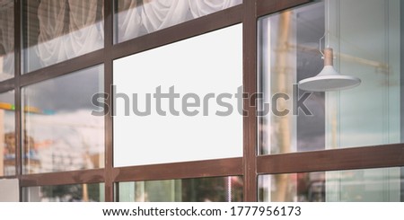 large white blank poster for mock-up hanging on glass window case of restaurant cafe of fashion store outdoor