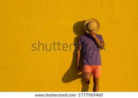 Young blond man with summer clothes, hat and sunglasses enjoying the summer