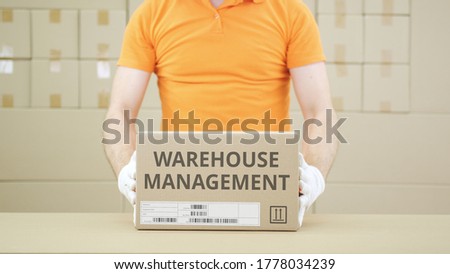 Putting carton with WAREHOUSE MANAGEMENT text on the table