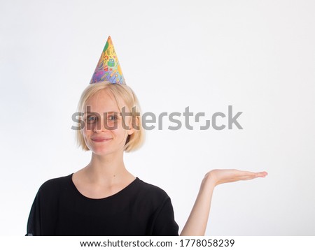 
Portrait of a young girl with blue eyes and blond hair. birthday hat. The girl has an emotion of joy on her face. birthday during quarantine. Place for text.