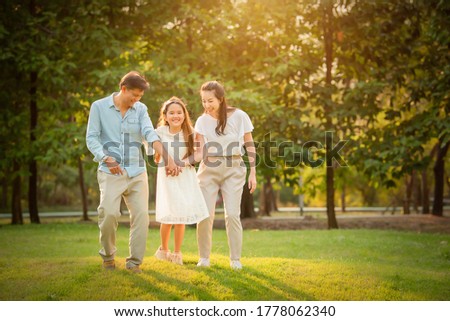 Happy family playing on the grass in the park at sunset. The concept of a happy family.