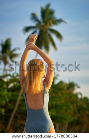 woman standing in the sea arms stretched out at sunrise 