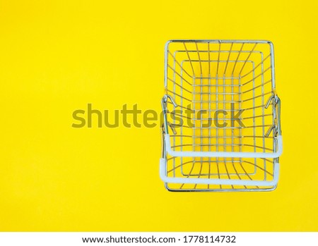 metal shopping basket on a yellow background. concept of buying, selling, discounts.