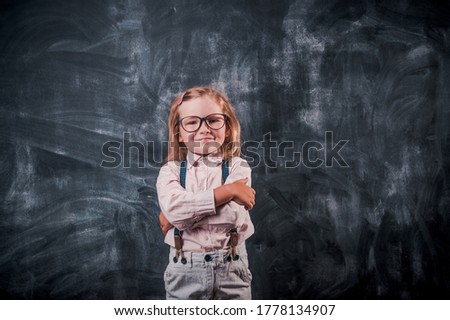 Smart little kid ready to go to school. Kid in glasses against blackboard.