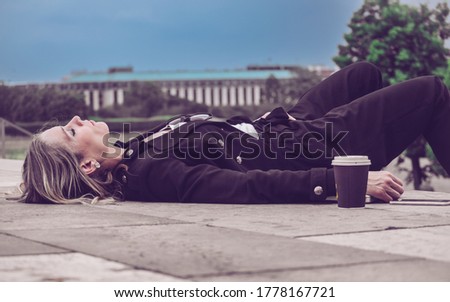 Young girl, elegantly dressed, sleeping outside in the open air, leaning on the floor next to her coffee. Business Woman / Student Concept. Royalty-Free Stock Photo #1778167721