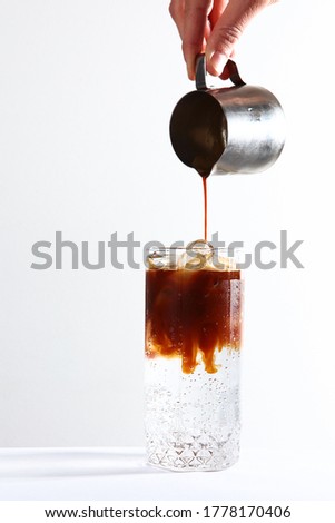 Soft drink based on coffee and mineral water. Coffee is poured into ice water. A thirst-quenching drink. Vertical photo. Copy space.