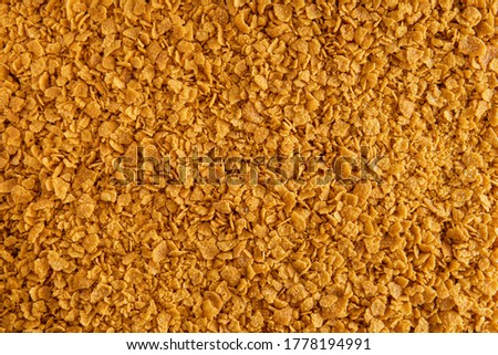 Abstract background of golden breadcrumbs replacement made from yellow gluten-free cornflakes. view from above texture top view