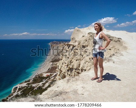 The girl stands on the white mountains next to the sea.
