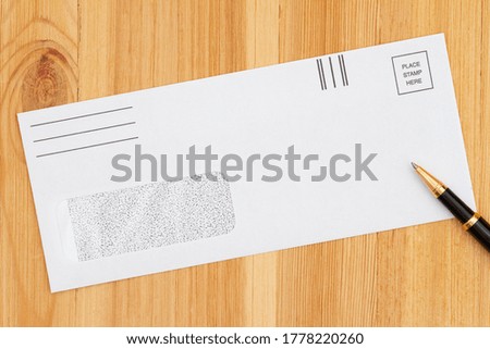Blank business envelope with pen on a wood desk mockup for your message