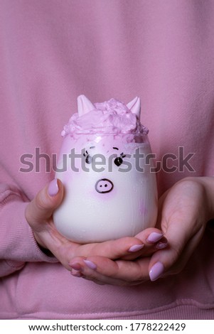 Piggy whipped milk in woman hands against the pink hoodie