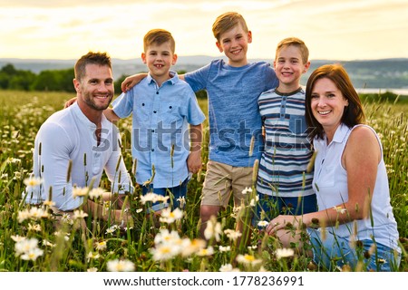 A Happy family on daisy field at the sunset having great time together