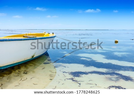 Perspective view on yellow fisher boat anchoring on african beach, low tide, shallow depth of field