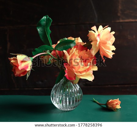 Bouquet of beautiful orange roses on a green table on a dark background