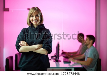 Young girl designer and his creative design team at the office during developing a new project, pink neon background 