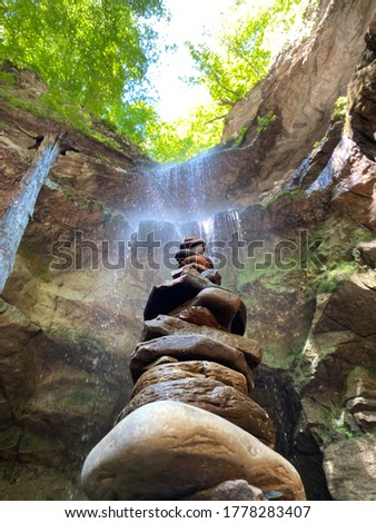Beautiful waterfall in cave like structure behind small rock statue.