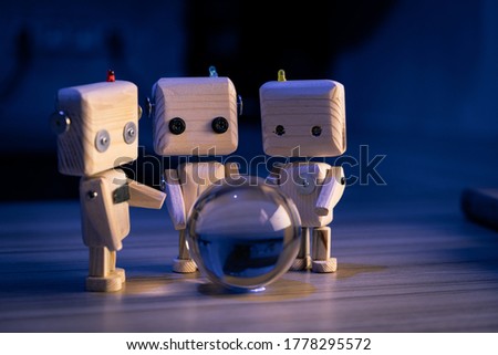 A small wooden toy robots looks at a glass ball in the dark. wallpaper, blured background. low light