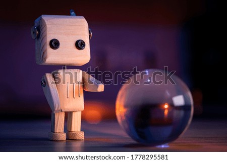 A small wooden toy robot looks at a magic glass ball in the dark. wallpaper, blured background. low light