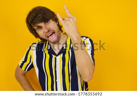 Portrait of a crazy boy showing tongue horns up gesture, expressing excitement of being on concert of band.
