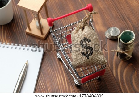 A bag of money in the shopping carts on a wooden background