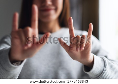 Closeup image of a woman making and showing love hand sign with feeling happy