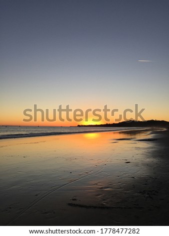 Orange half sun water reflection, sunset in Santa Barbara, California. Pacific ocean shallow beach with sun reflection in the water. falling star over ocean, peaceful, mesmerising, tranquil and calm