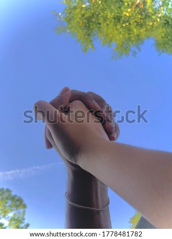 Hand holding in the air with sky background and trees or leaves