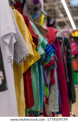 T-shirts of different colors hang on hangers in the store. High quality photo