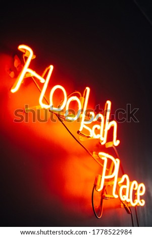 red neon sign hookah place on black wall background