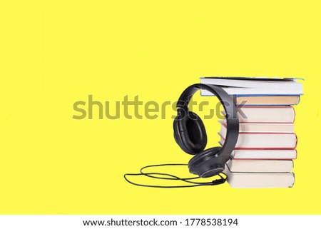 Books and headphones on a yellow background in the audiobook concept.