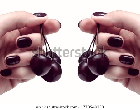                   female hand with cherry-colored manicure with cherry in hands,  summer manicure concept             