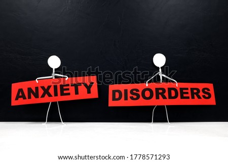 Human stick figure holding red Anxiety Disorders word banner. Black background.