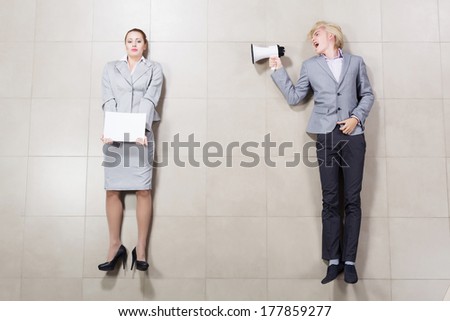 Angry businessman shouting in megaphone on his colleague