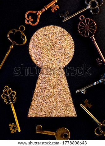 Many different antique keys and a keyhole. Finding the right key to the lock, concept. Retro vintage brass keys on a black background