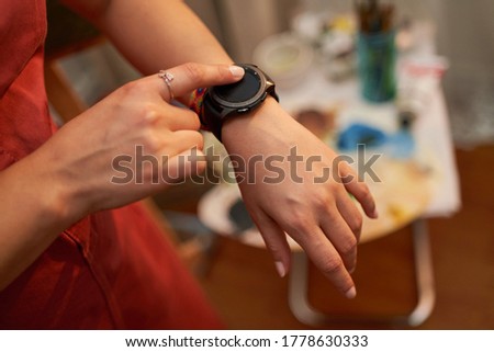 Top view of female hands setting smart watch. Close up of woman hands using smartwatch. Wearable technology. Dramatic ambient light, golden hour.