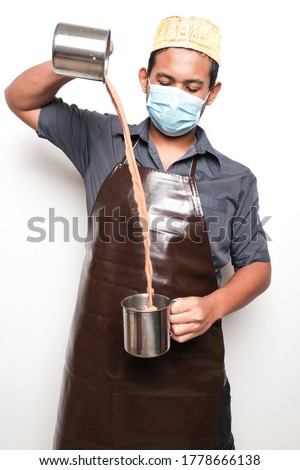 A picture of men preparing "teh tarik". Sweet milk tea been pull for mix well and create foam that is famous in Malaysia and South Asia region. Royalty-Free Stock Photo #1778666138