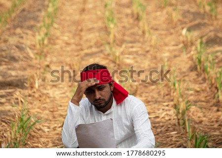 Stressed farmer with unpaid bills on agricultural field Royalty-Free Stock Photo #1778680295