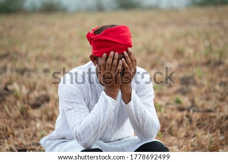 Depressed farmer covering his face with both hands on agricultural field Royalty-Free Stock Photo #1778692499