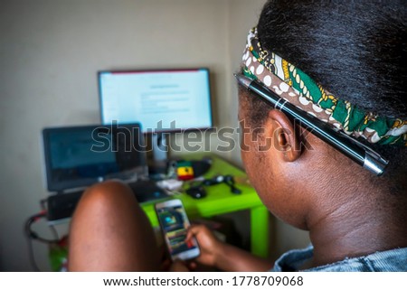 photo of the side of black person at workstation indoors,working from home,using smartphone,sharing content on social media platforms,using tracking app.focus on ear on head
