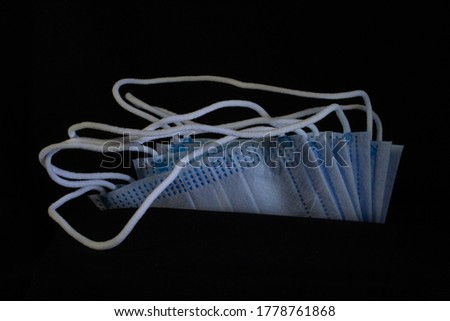 some new blue and white surgical masks isolated on a black background with white ends showing